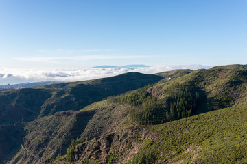 Fototapeta na wymiar Sunset in the highlands of La Gomera. View direction Valle Gran Rey. In the background the Island La Palma. Clouds from trade winds over the mountains on La Gomera. The clouds comes from the Azores