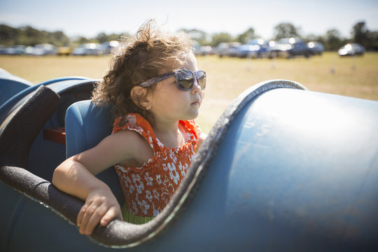 Girl sitting in barrel cart, wearing sunglasses 