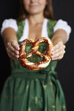 Young woman in Dirndl holding pretzel