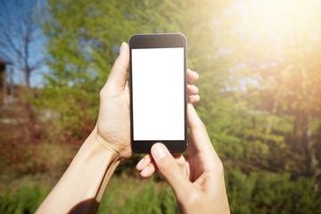 Woman chatting on cell phone while resting outside in the country. Cropped view of female hands holding smart phone against green nature background while walking in the park on sunny day. Film effect
