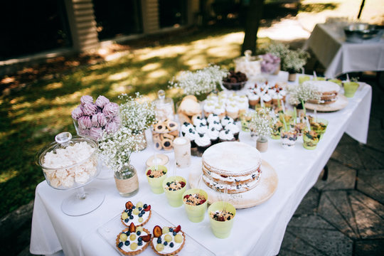 Delicious wedding reception candy bar Dessert table for a wedding outdoor party. Ombre cake, cupcakes, sweetness and flowers