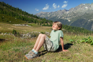 Naklejka na ściany i meble The happy six years boy blinks in sunlights on mountain slope