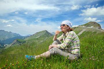 Young woman sitting on a mountain with clover flower in his hand