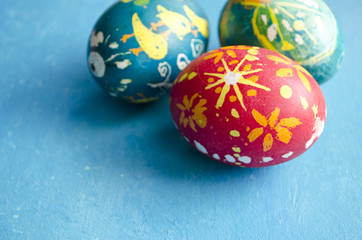 Three colorful handmade easter eggs isolated on a blue background