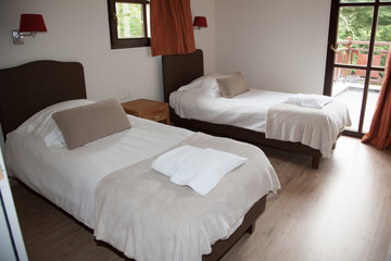 A bedroom in a new house with two single beds and large window&#39;s.