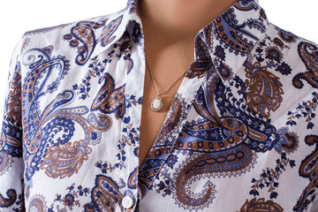Floral shirt and small pendant. Accessory and shirt on mannequin. Lady's stylish accessory on display. Delicacy and style.