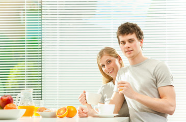 Obraz na płótnie Canvas Young casual couple have breakfast with coffee and fruit with venetian blind window