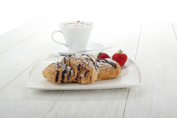 chocolate croissants bread on plate with strawberry and coffee foam