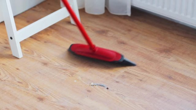 woman with broom cleaning floor at home