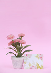 Flower pot with blank paper note on the pink background