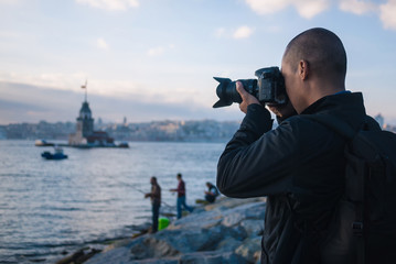 Male photographer in Istanbul, Turkey, taking photo of Maiden's Tower in Istanbul, Turkey on Bosphorus River