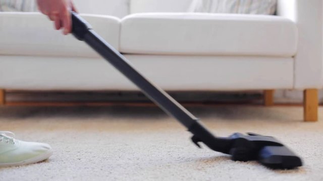 woman with vacuum cleaner cleaning carpet at home