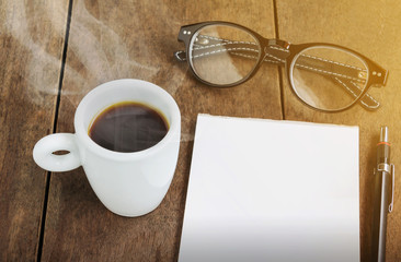 White cup of black coffee with note and pencil on wood table