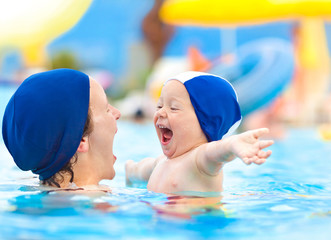 Obraz premium happy child and mom with swimming pool cap have fun in a pool