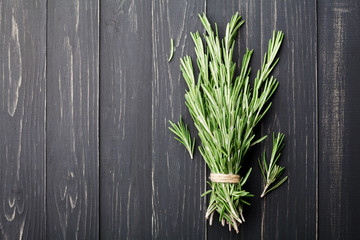 Bunch of rosemary plant on black rustic table from above, fresh herbs