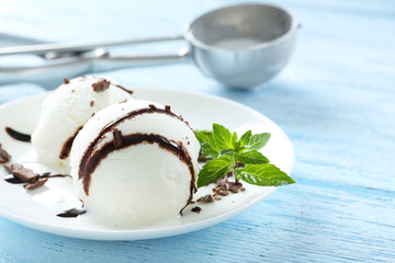 Sweet ice cream in plate on blue wooden background