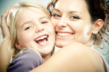 Beautiful brunette woman with young blond girl on grey background