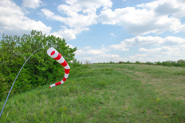 Air field direction sign and a wind force windsock against the  blue sky with clouds