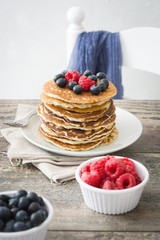 Pancakes with blueberries and raspberries on rustic wood
