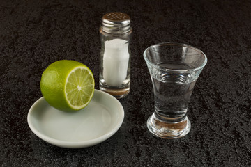 Silver tequila with lime on black background