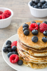 Pancakes with blueberries and raspberries on rustic wood
