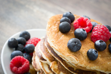 Pancakes with blueberries and raspberries on rustic wood
