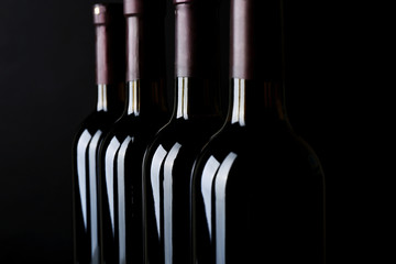 Wine bottles in a row on black background, close up