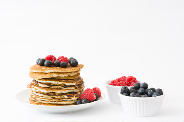 Pancakes with blueberries and raspberries isolated on white background
