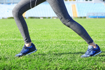 Sports woman legs in sneakers on grass outdoor