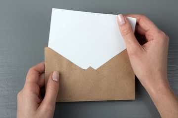 the woman took the letter out of the envelope on a gray wooden background