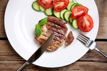 Roasted beef fillet and fresh vegetables on plate, on wooden background