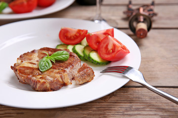Roasted beef fillet and fresh vegetables on plate, on wooden background