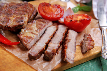 Roasted beef fillet and vegetables on cutting board, on wooden background
