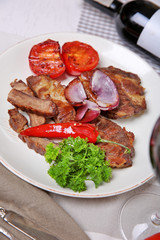 Roasted beef fillet and grilled vegetables on plate, on wooden background