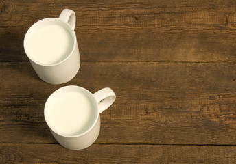 Two cups with cold milk on the wooden table