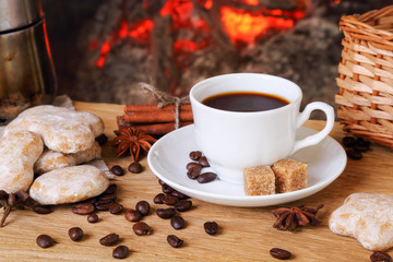 Cup of coffee with spices  in the background of a burning firepl