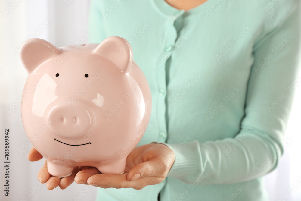 Poster Woman holding piggy bank in hand. Financial savings concept