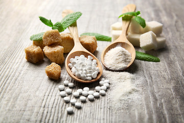 Pile of brown sugar cubes and stevia  on grey wooden background - obrazy, fototapety, plakaty