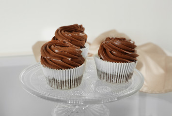 Three chocolate cupcakes on light glass background, close up