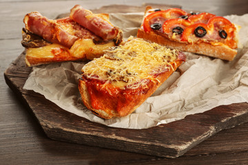 Hot pizza baguettes with ham, bacon and salami on wooden table