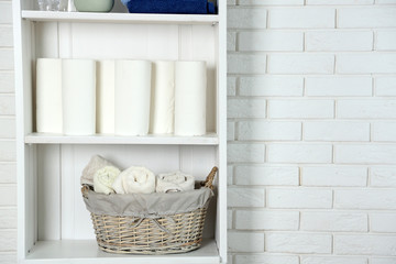 Fototapeta na wymiar Bathroom set with towels and basket on a shelf in light interior