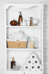 Bathroom set with towels, toothbrushes and basket on a shelf in light interior