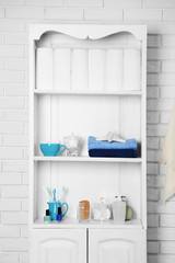 Bathroom set with towels, toothbrushes and sponges on a shelf in light interior