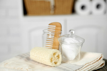 Fototapeta na wymiar Bathroom set with towels, sponges and comb on stool in light interior