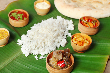 Boiled rice with vegetables and flat bread on banana leaf, close up