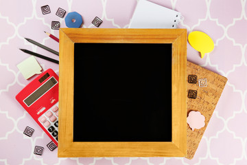 Small school blackboard with stationery on patterned background