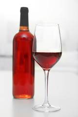 Glass of red wine with bottle on blurred interior background