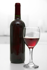 Glass of red wine with bottle on blurred interior background
