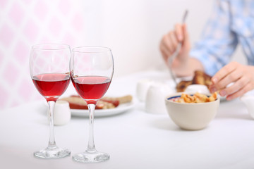 Dinner with glasses of wine on light blurred background