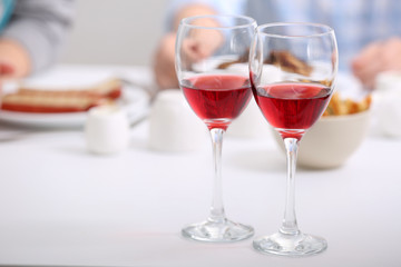Dinner with glasses of wine on light blurred background